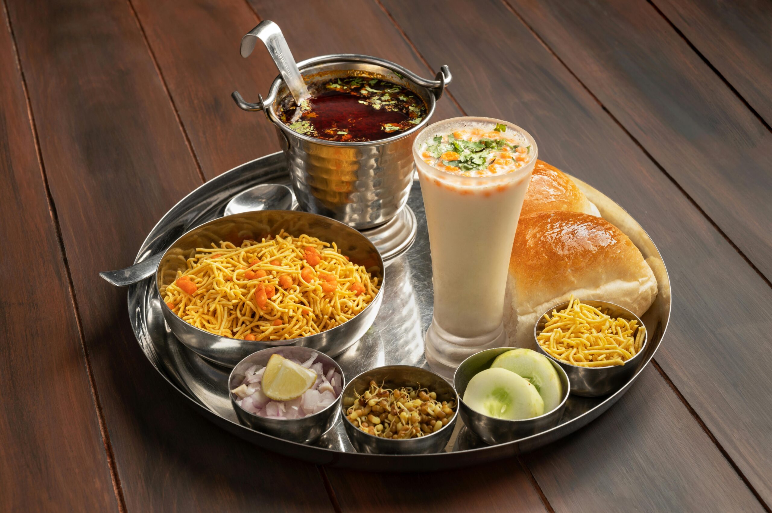 A deliciously arranged Misal Pav platter served with lassi, showcasing authentic Maharashtrian cuisine.