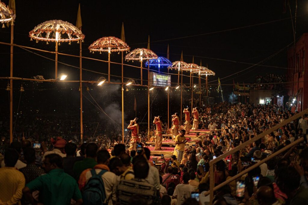 Evening ritual ceremony on the Ghats of Varanasi with a large crowd attending.